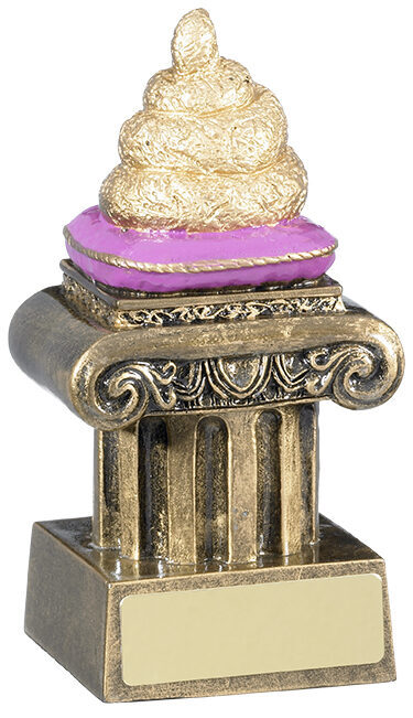 Golden textured poo emoji-style trophy with swirled design sitting on purple velvet cushion atop ornate Corinthian column base with engraving plate