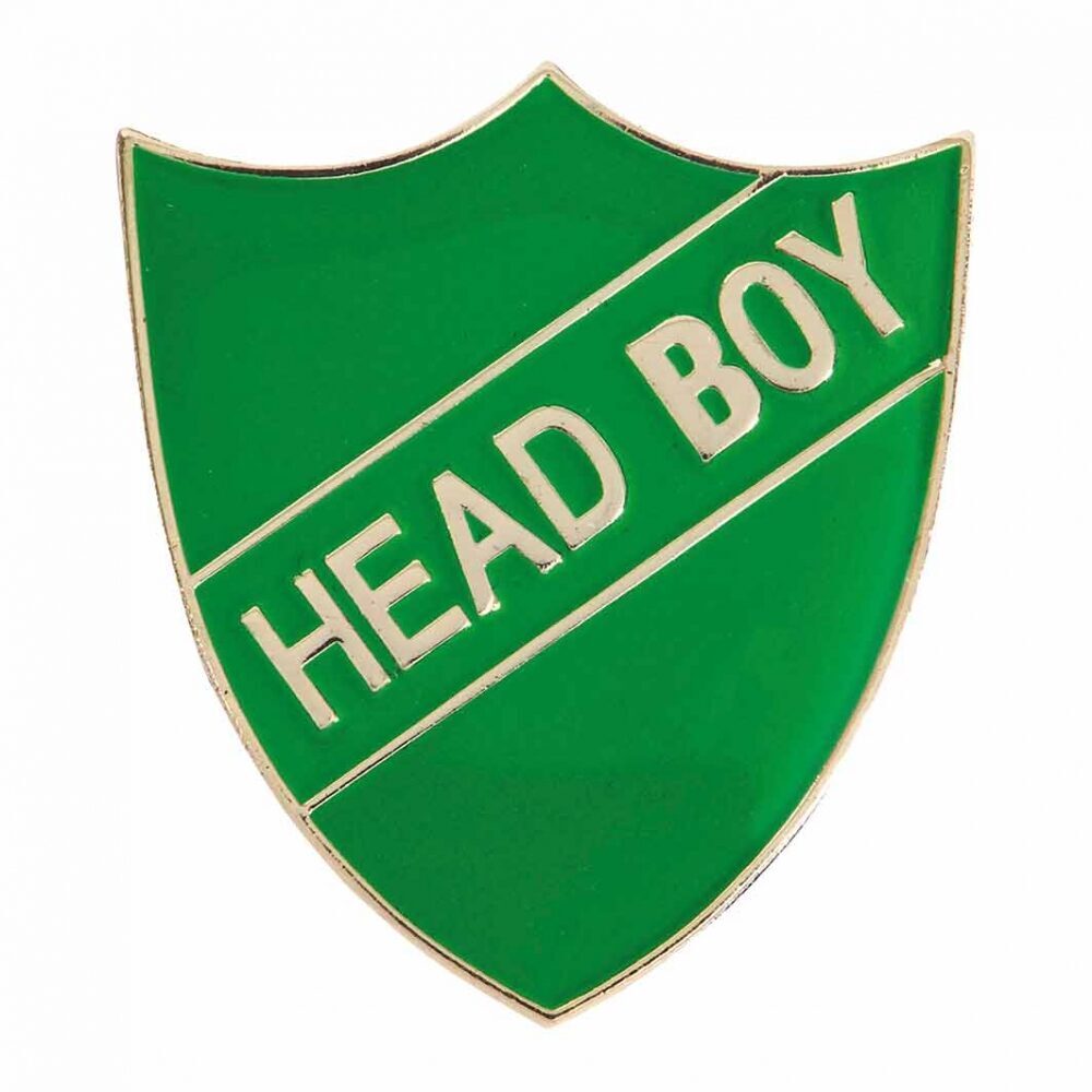 Green shield-shaped enamel pin badge with gold border displaying white 'HEAD BOY' text on diagonal banner design against white background