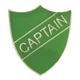 Green shield-shaped enamel captain badge with gold-coloured border and 'CAPTAIN' text displayed on a diagonal banner across the green enamel surface