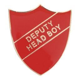 Red shield-shaped enamel badge with gold 'DEPUTY HEAD BOY' text across a diagonal banner, featuring polished edges and pin back fastening