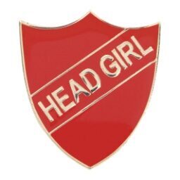Red shield-shaped enamel badge with gold 'HEAD GIRL' text across a diagonal banner, featuring polished edges and pin back fastening