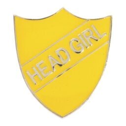 Bright yellow shield-shaped enamel school badge displaying 'HEAD GIRL' in raised silver lettering, with polished metal border and secure pin attachment
