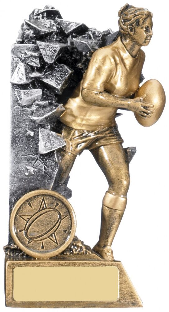 A trophy featuring a gold-colored figure of a young athlete holding a ball, with a background of rocks and a circular emblem at the base.